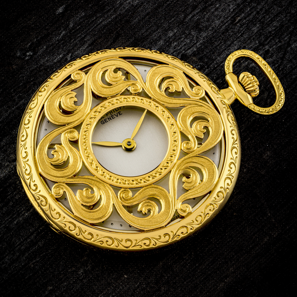 PATEK PHILIPPE. AN UNUSUAL AND POSSIBLY UNIQUE 18K GOLD POCKET WATCH WITH ORNATELY ENGRAVED CASE