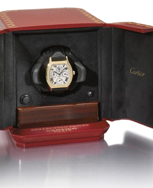 Cartier. A fine and large 18K gold tonneau-shaped self-winding two time zone perpetual calendar wristwatch