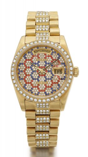 Rolex A YELLOW GOLD AND DIAMOND-SET AUTOMATIC CENTRE SECONDS WRISTWATCH WITH DIAMOND, RUBY AND SAPPHIRE-SET DIAL AND BRACELET REF 18048 CASE 8202831 DAY-DATE CIRCA 1985